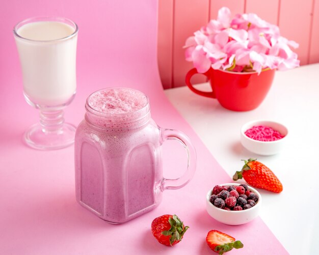 смешанный ягодный молочный коктейль со сливочным молоком клубника замороженная красная и черная смородина на столе