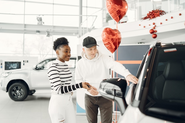 Free photo mixed couple. shot of an international couple shooses a car. african woman with caucasian man.