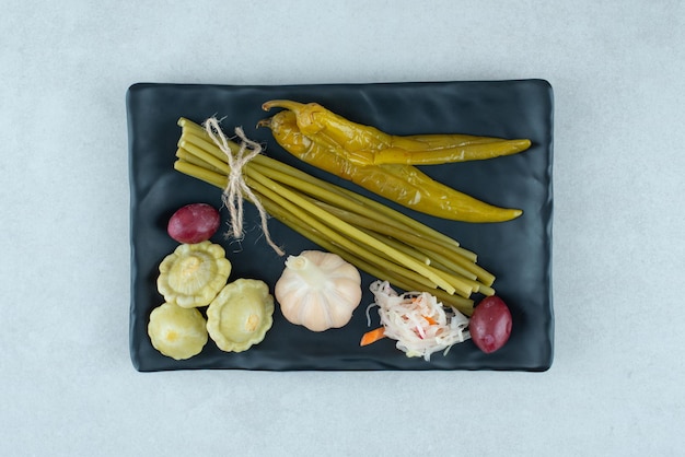 Mixed fermented vegetables on black plate.