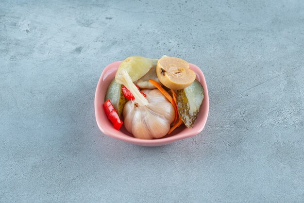 Mixed of fermented vegetables in a plastic bowl on the blue surface