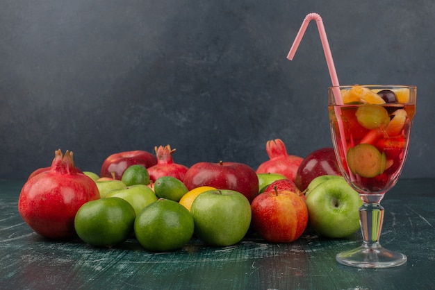 Mixed fresh fruits and glass of juice on marble table