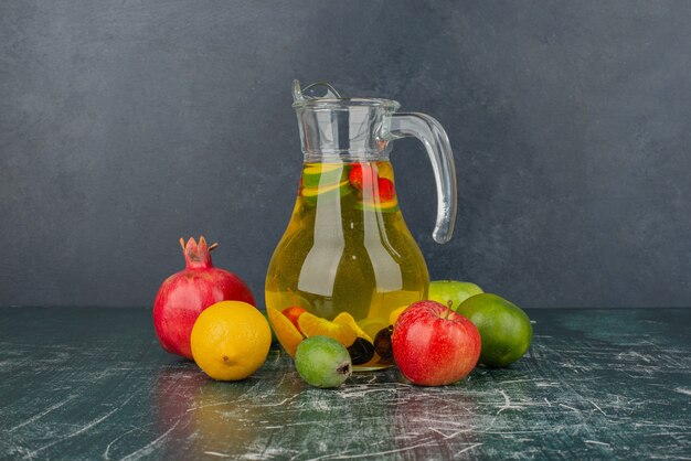 Mixed fresh fruits and glass of juice on marble table.