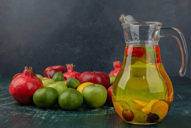 Mixed fresh fruits and glass of juice on marble table.