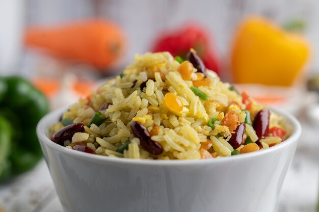 Mixed fried rice in a cup on a white wooden floor.