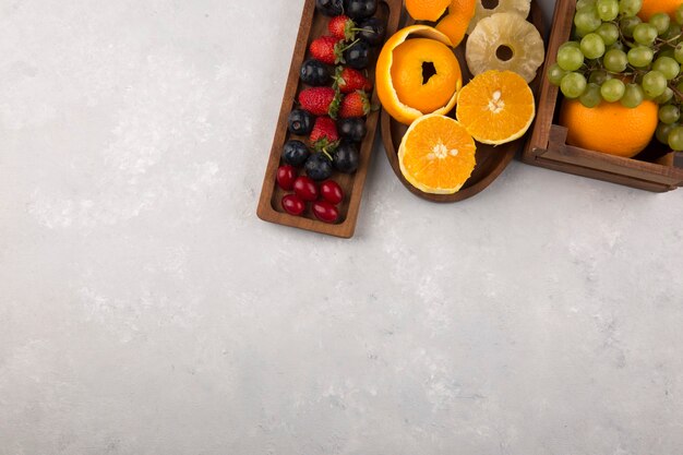 Mixed fruits and berries in wooden platters on the top corner