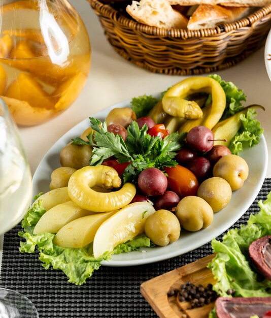 Mixed marinated vegetables and fruits inside white plate.