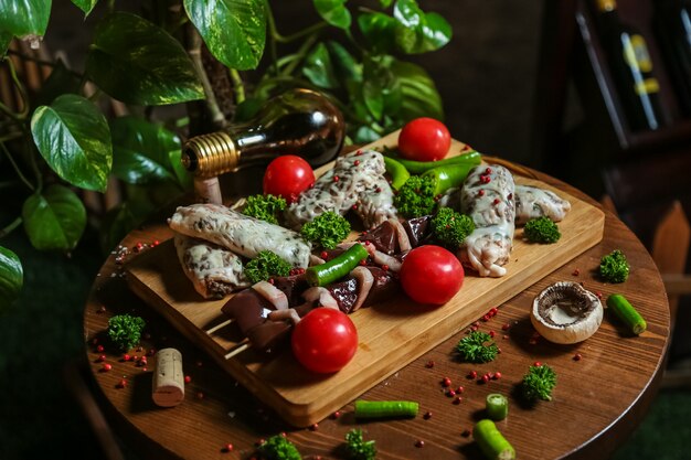 Mixed meat on the wooden board with tomatos, mushrooms and pepper