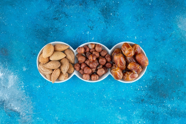 Free photo a mixed of nuts in a bowl , on the blue table.