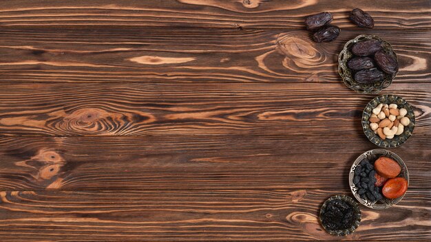 Mixed nuts; dates and dried fruits for ramadan festival on wooden backdrop