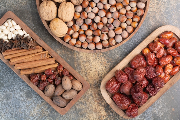Mixed nuts with cinnamon sticks and dried fruit on wooden plate. High quality photo