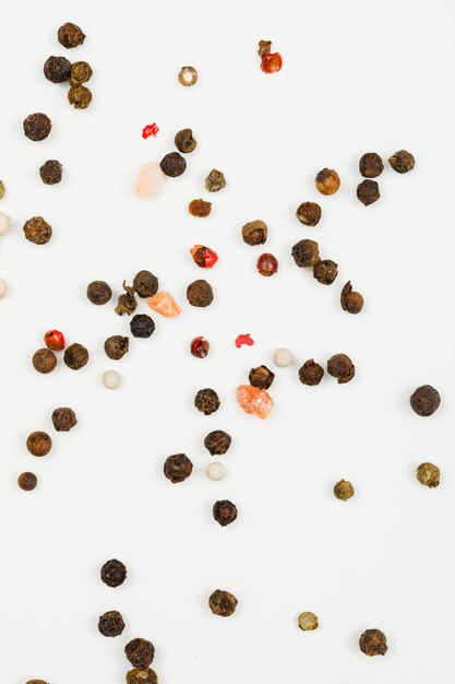 Mixed peppercorns on white. flat lay. vertical.