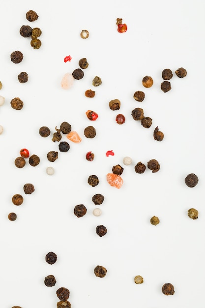 Mixed peppercorns on white. flat lay. vertical.