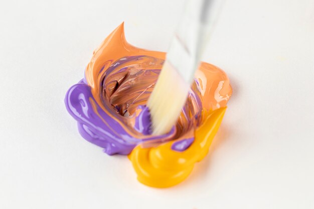 Mixed purple and orange paint on white table