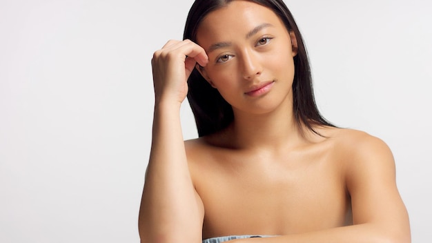 Mixed race asian model in studio beauty shoot Model poses to a camera straight hair Ideal skni and no makeup makeup Head and shoulders crop