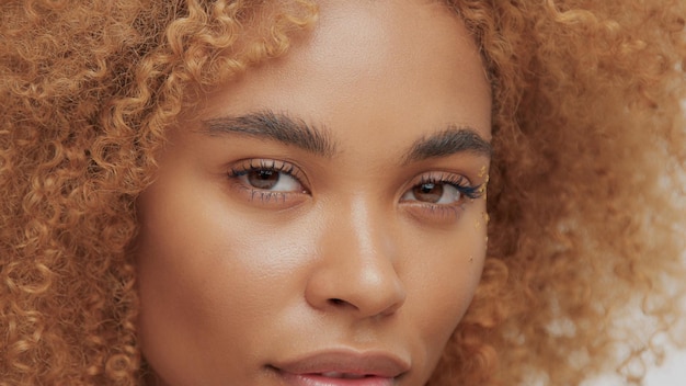 Mixed race black blonde model with curly hair eyes closeup watching to the camera