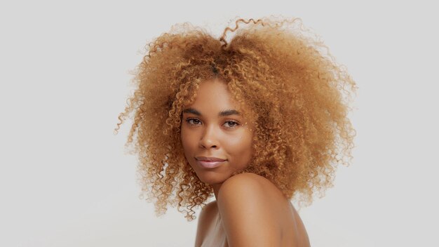 Mixed race black blonde model with curly hair happy smiling touching it