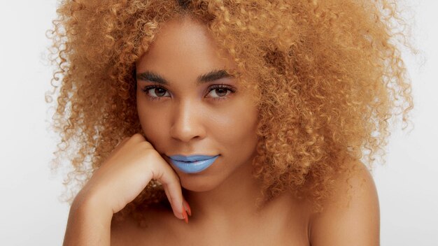 Mixed race black blonde model with curly hair watching to the camera wears bright blue lipstick
