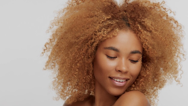 Mixed race black blonde model with curly hair watching down Ideal skin model