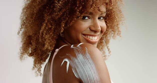 Mixed race black woman with blonde curly hair in studio with a cream on her skin