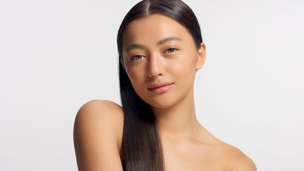 Mixed race model with straight hair watching to the camera Ideal skin natural glowy makeup Head and shoulders crop