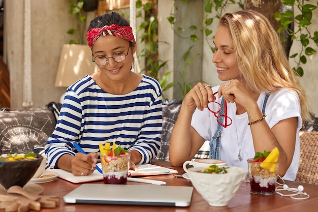 Mixed race student translate foreign words, write transcription into notepad