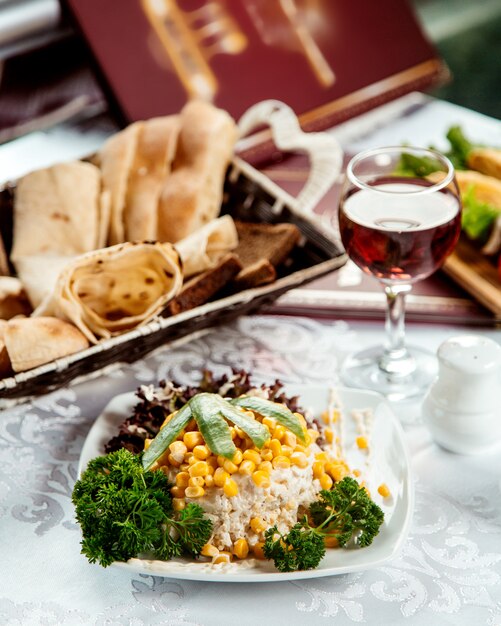 Mixed salad with corn on top and bread basket