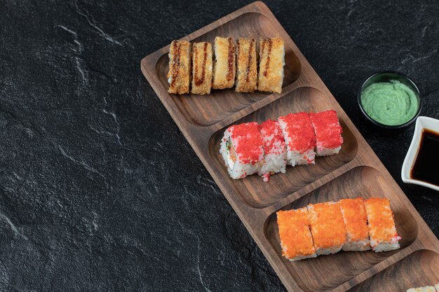 Mixed sushi set on a wooden board with soy sauce aside.