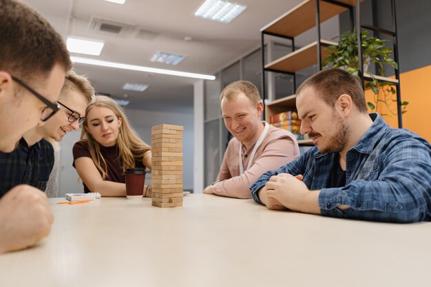 混合チームがオフィスで木製のゲームをブロック