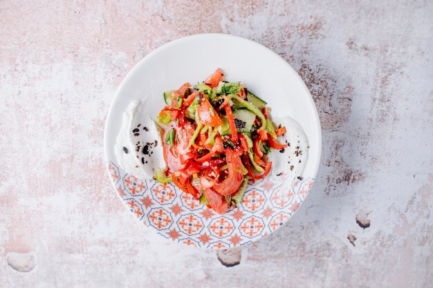 Mixed vegetable salad with colorful bell peppers inside decorative plate.