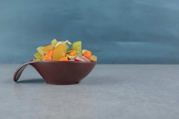 Mixed vegetable salad in a wooden cup on the concrete table.