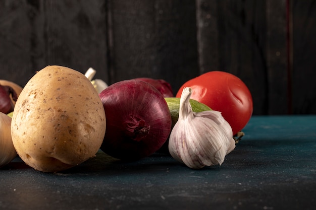 Овощное ассорти, включая чесночные перчатки, картофель, лук и помидоры.