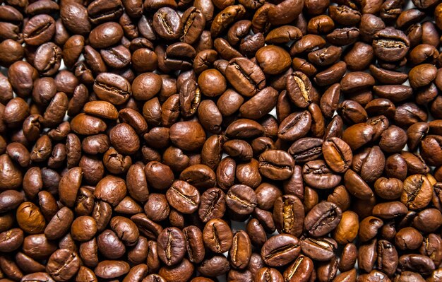 異なる種類のコーヒー豆の混合物。コーヒーの背景。焙煎コーヒー豆。白い背景にあるコーヒー豆