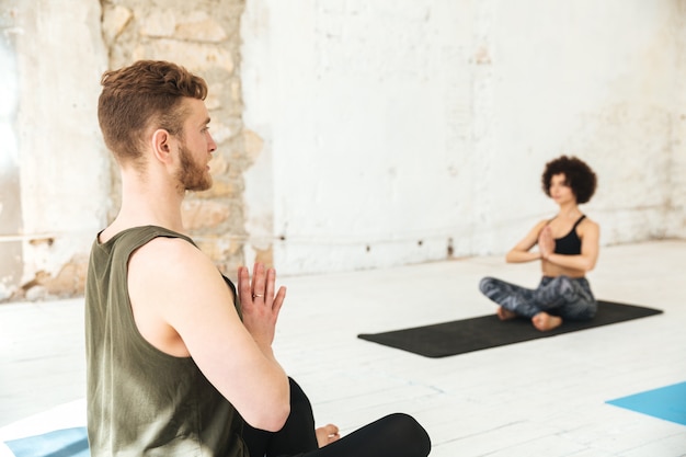 Foto gratuita istruttore mlale che fa lezione di yoga con i suoi studenti