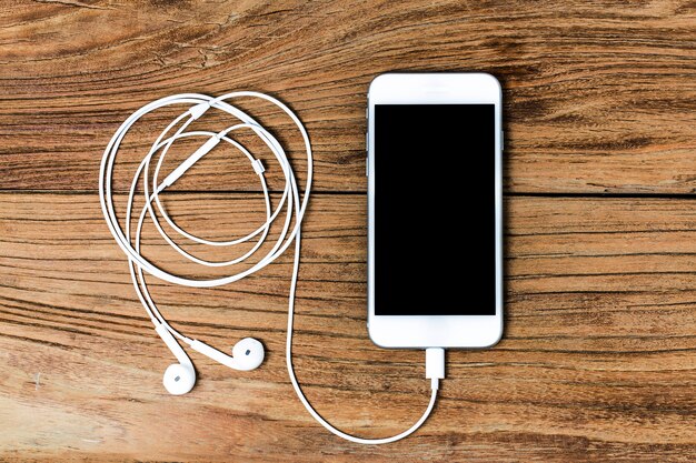 Mobile phone and earphones on wooden background