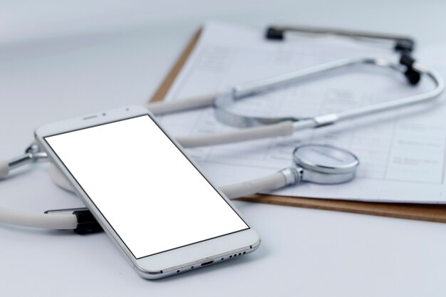 Мобильный телефон, стетоскоп и файл диаграммы на рабочем столе (мобильные медицинские, карманные концепции врача)