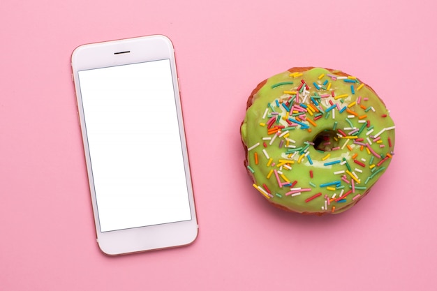 Premium Photo | Mobile phone and sweet green donut on a pink background