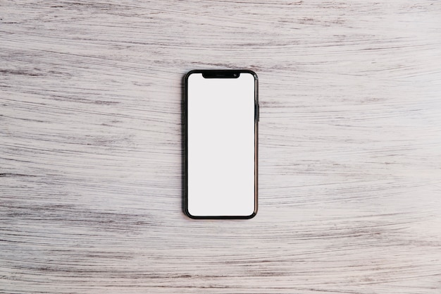 Мобильный телефон с белым белым экраном на деревянной столешнице