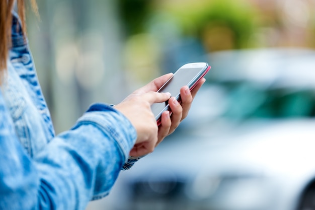 Mobile phone in a woman's hand. Outdoor image.