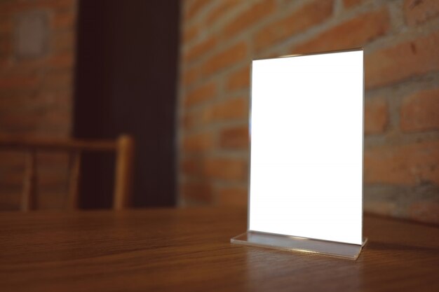 Mock up menu frame standing on wood table in bar restaurant cafe. space for text.