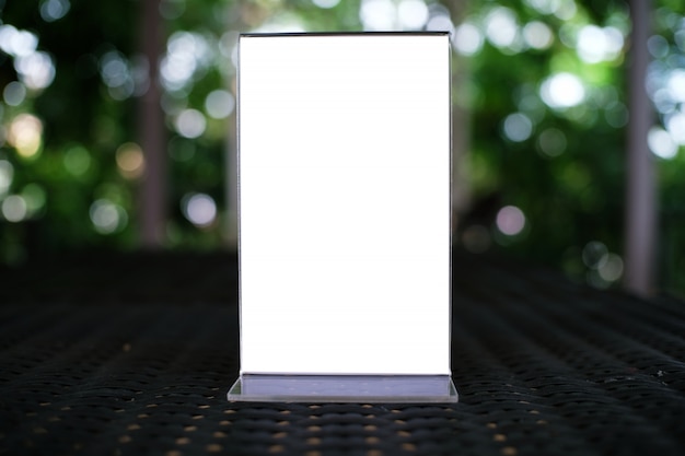 Mock up menu frame standing on wood table in bar restaurant cafe. space for text.