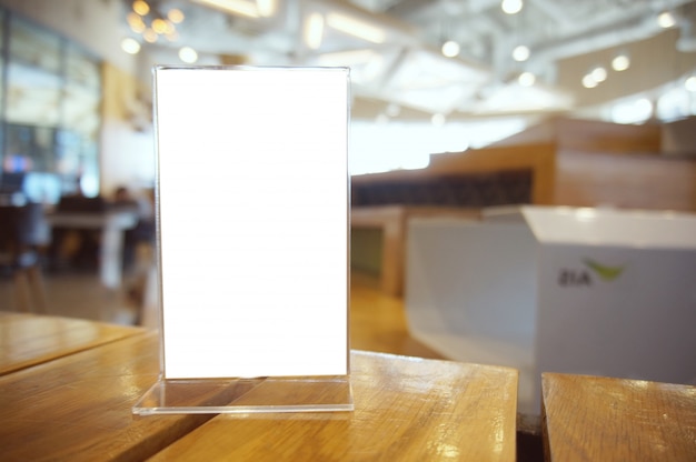 Mock up menu frame standing on wood table in bar restaurant cafe. space for text