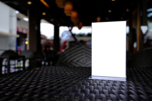 Mock up menu frame standing on wood table in bar restaurant cafe. space for text.