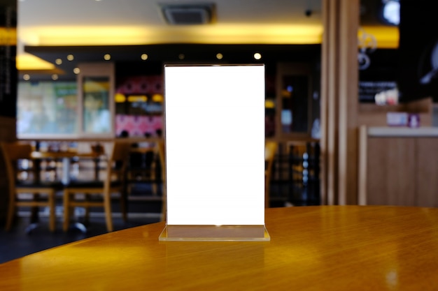 Mock up menu frame standing on wood table in bar restaurant cafe. space for text.