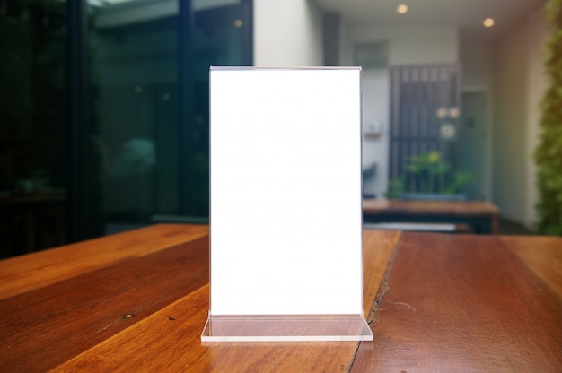 Mock up menu frame standing on wood table in bar restaurant cafe. space for text.