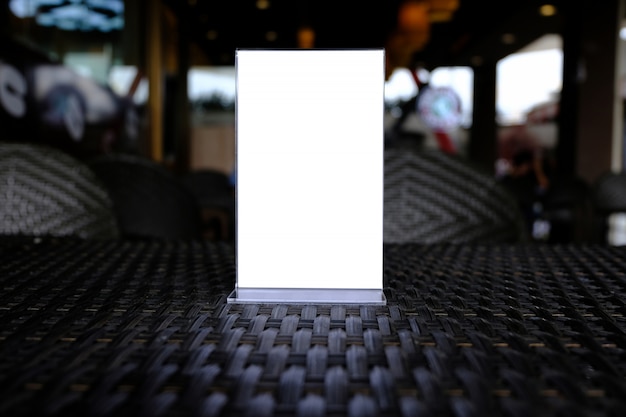 Mock up menu frame standing on wood table in bar restaurant cafe. space for text.