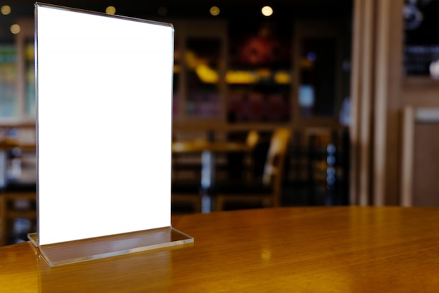 Mock up menu frame standing on wood table in bar restaurant cafe. space for text.