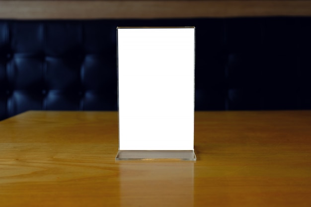 Mock up menu frame standing on wood table in bar restaurant cafe. space for text.