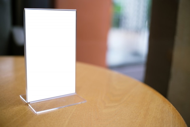 Mock up menu frame standing on wood table in bar restaurant cafe. space for text.