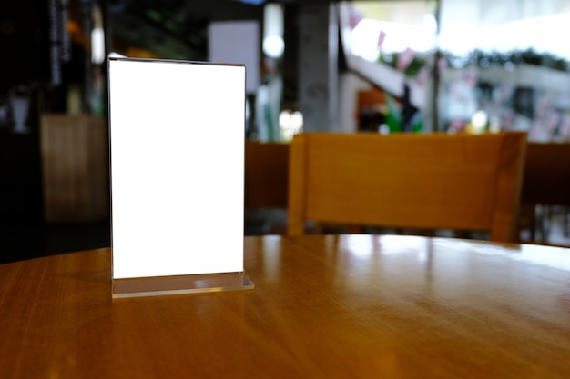 Mock up menu frame standing on wood table in bar restaurant cafe. space for text.