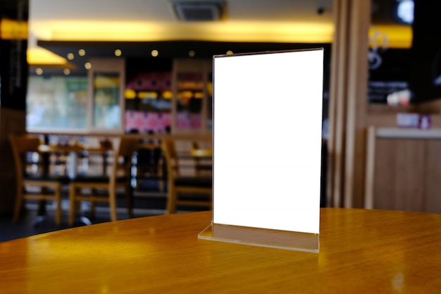 Mock up menu frame standing on wood table in bar restaurant cafe. space for text.